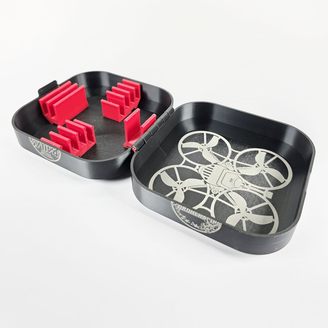 Open 3D-printed tiny whoop drone case in black PETG with red battery clips and a laser-engraved drone lid