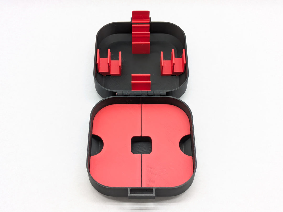 Top-down view of the open Elite case with red battery clips in the lid and red storage lids in the base