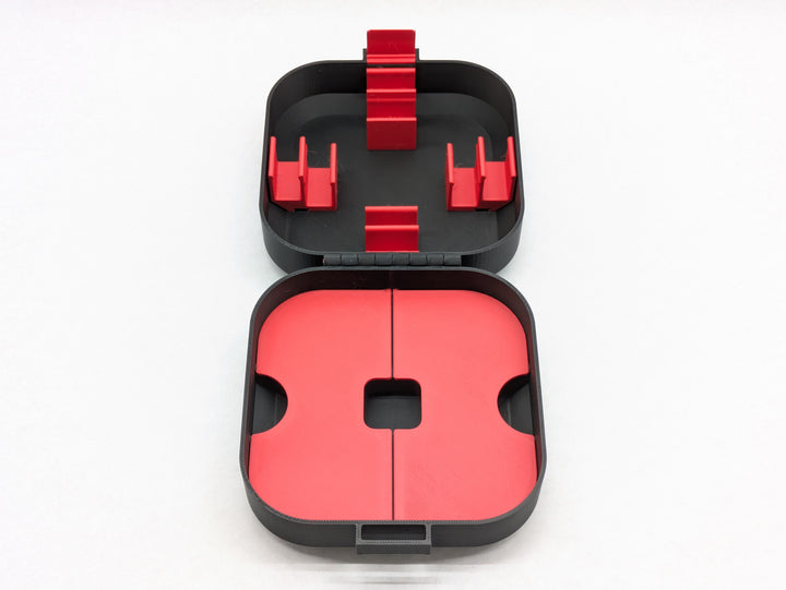 Top-down view of the open Elite case with red battery clips in the lid and red storage lids in the base